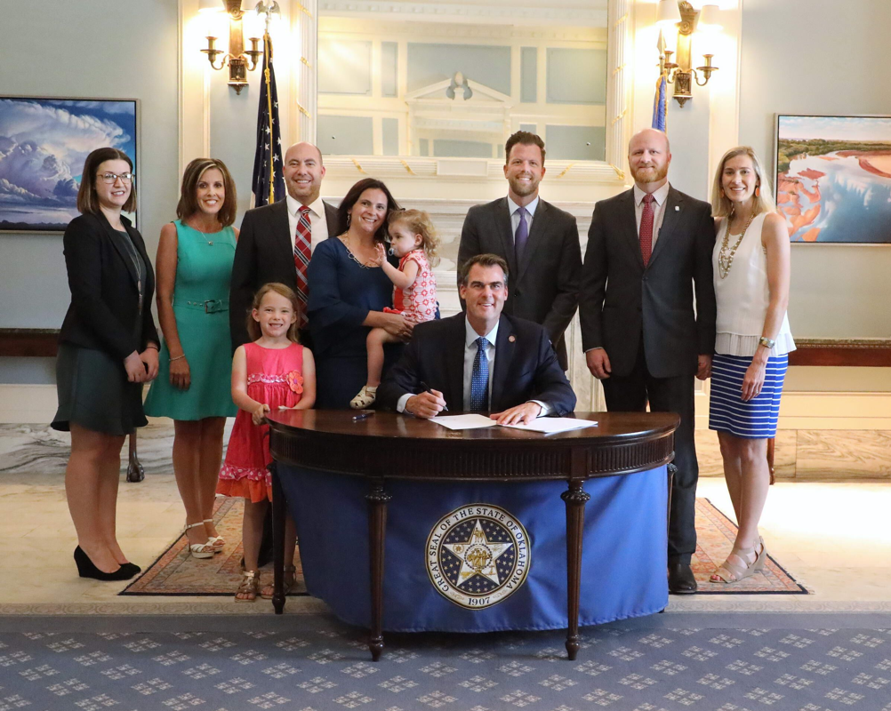 Legislative Assistant Meagan Hansen, Gayle Garrett with Surrogate Solutions, Andy Long, Laura Long, daughters Maddie and Della, Gov. Kevin Stitt, Rep. Jason Dunnington, D-Oklahoma City, Sen. Brent Howard and Jennifer Howard gathered in the Governor’s Blue Room for the recent ceremonial signing of legislation creating the Oklahoma Gestational Agreement Act.  Howard and Dunnington were principal authors of the legislation.